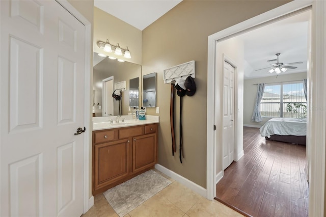 ensuite bathroom featuring wood finished floors, a ceiling fan, vanity, baseboards, and ensuite bath