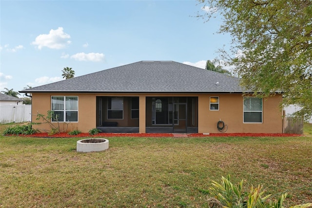 rear view of property with a lawn, a sunroom, roof with shingles, fence, and stucco siding