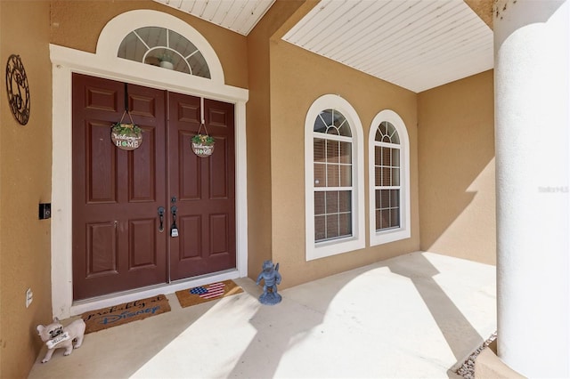 entrance to property with covered porch and stucco siding