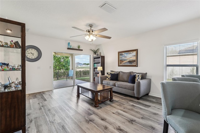 living area featuring ceiling fan, visible vents, baseboards, and light wood-style flooring