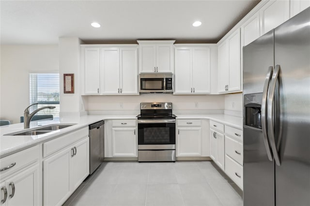 kitchen with appliances with stainless steel finishes, white cabinetry, light countertops, and a sink