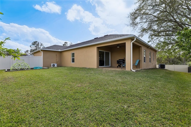 back of property with central AC, stucco siding, a lawn, and a fenced backyard