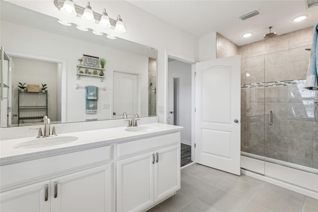 bathroom featuring double vanity, visible vents, a stall shower, and a sink