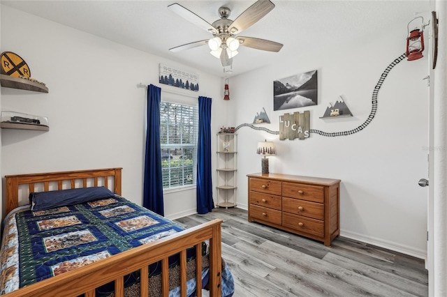 bedroom with a ceiling fan, wood finished floors, and baseboards