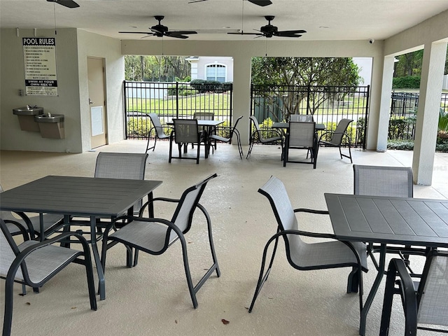 view of patio with outdoor dining area, fence, and ceiling fan