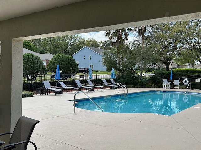 community pool with a patio and fence