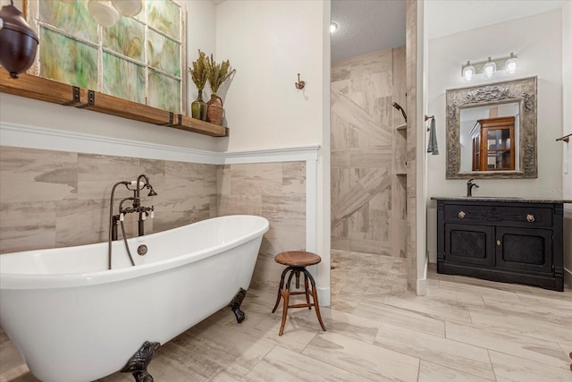 bathroom featuring tile walls, a textured ceiling, walk in shower, vanity, and a freestanding bath