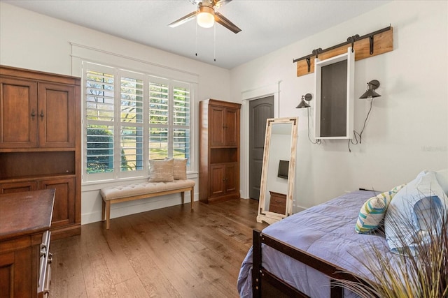 bedroom with light wood finished floors, baseboards, a barn door, and a ceiling fan