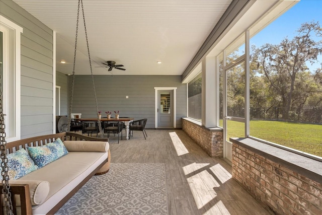sunroom featuring plenty of natural light, outdoor dining area, outdoor lounge area, and ceiling fan