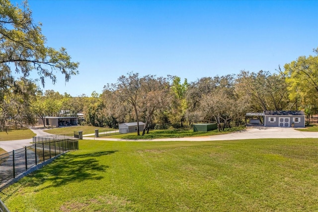 view of yard with an outdoor structure, a storage shed, fence, and concrete driveway