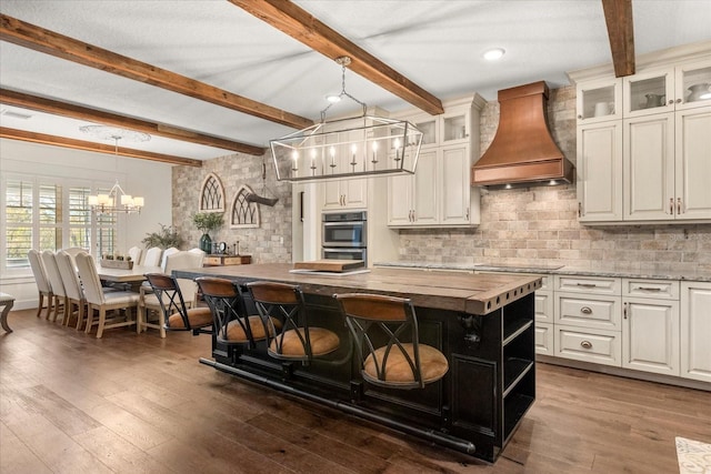kitchen featuring a notable chandelier, butcher block counters, custom exhaust hood, and dark wood-style flooring