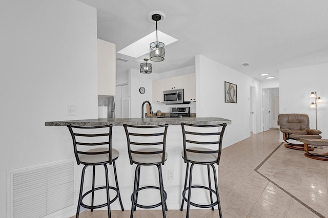 kitchen featuring a peninsula, dark countertops, a breakfast bar area, and stainless steel appliances