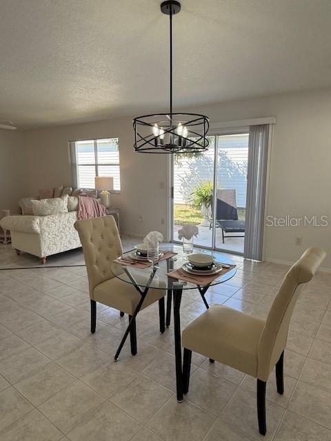 dining area featuring light tile patterned floors, baseboards, a chandelier, and a textured ceiling