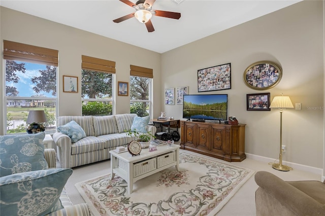 carpeted living room featuring ceiling fan and baseboards