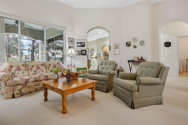 living area with a high ceiling, arched walkways, crown molding, and light colored carpet