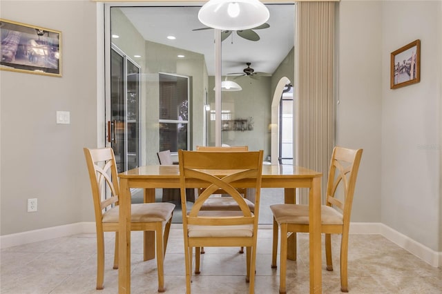 dining area with a ceiling fan, arched walkways, baseboards, and light tile patterned floors