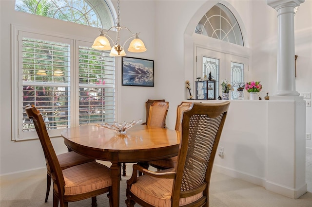 dining room featuring light carpet, ornate columns, baseboards, and an inviting chandelier