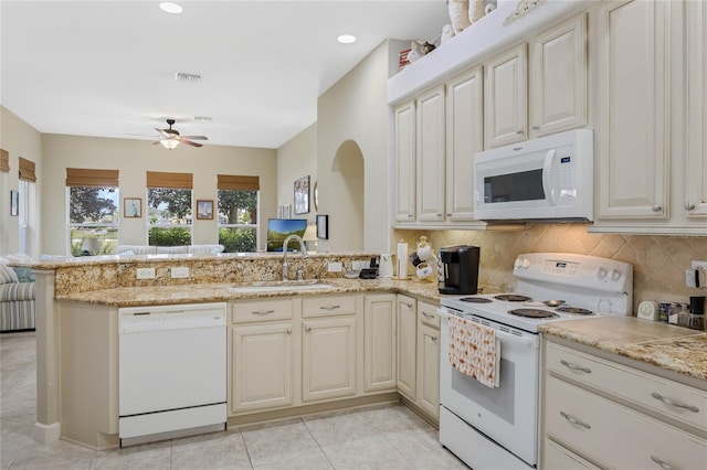 kitchen with a peninsula, white appliances, backsplash, and a sink