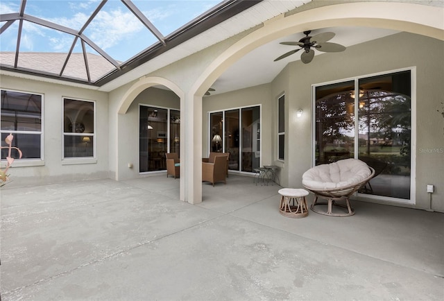 view of patio featuring ceiling fan and glass enclosure