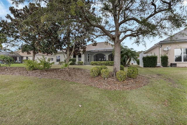 view of front of house with a front lawn, a lanai, and stucco siding