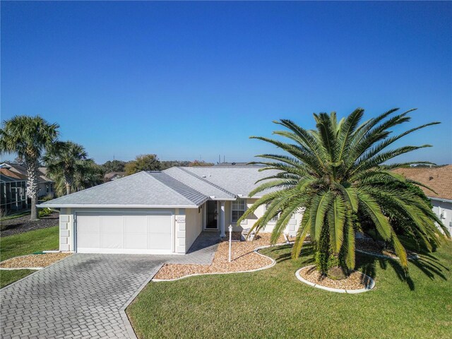 view of front of house with roof with shingles, an attached garage, decorative driveway, and a front yard