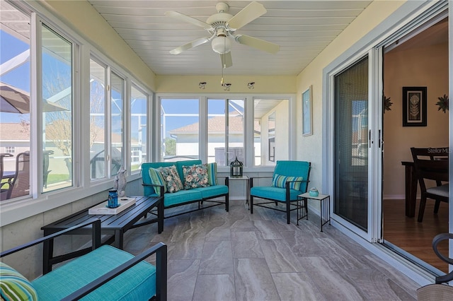sunroom / solarium with baseboards, a ceiling fan, and an outdoor hangout area