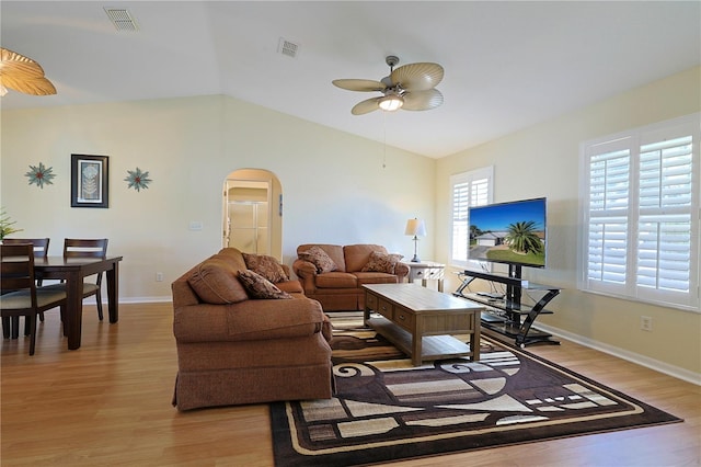 living area with ceiling fan, light wood-style floors, arched walkways, lofted ceiling, and visible vents