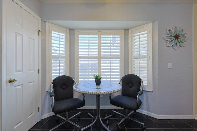 sitting room featuring dark tile patterned floors, baseboards, and a textured wall