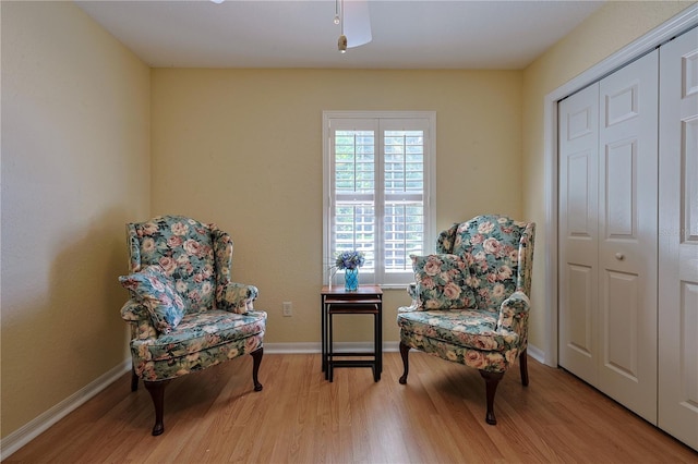 living area featuring baseboards, a ceiling fan, and wood finished floors