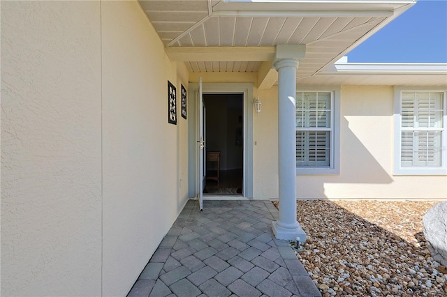 view of exterior entry with a patio and stucco siding