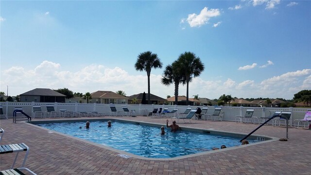 community pool with a patio area, fence, and a residential view