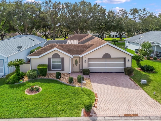 view of front of home with an attached garage, decorative driveway, a front yard, and stucco siding