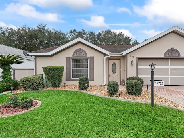 ranch-style house with a garage, a shingled roof, decorative driveway, stucco siding, and a front lawn