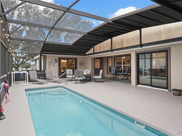 outdoor pool featuring glass enclosure and a patio