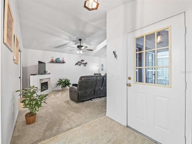 foyer with light tile patterned flooring, light carpet, a fireplace, and ceiling fan