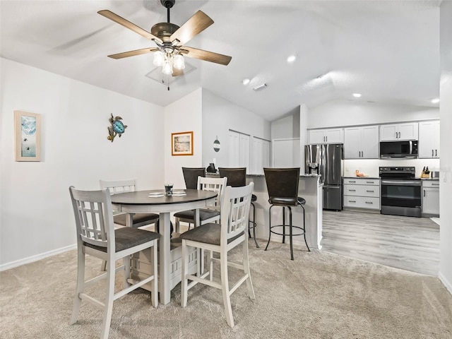 dining space featuring vaulted ceiling, ceiling fan, baseboards, and light colored carpet