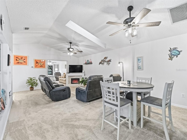 dining room with visible vents, ceiling fan, light carpet, and a premium fireplace