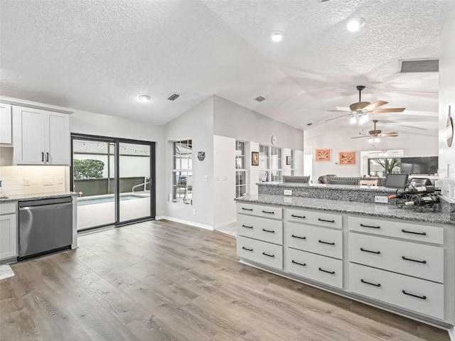 kitchen featuring lofted ceiling, white cabinetry, open floor plan, and dishwasher