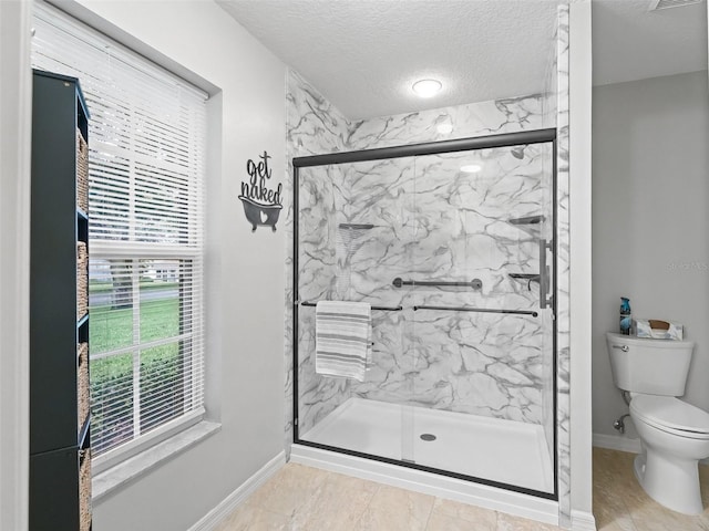 bathroom featuring baseboards, toilet, a textured ceiling, and a marble finish shower