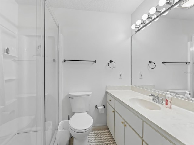 bathroom featuring baseboards, toilet, a textured ceiling, vanity, and a shower stall