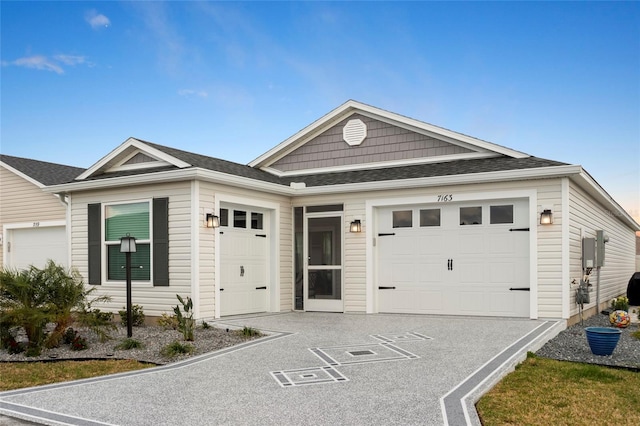 ranch-style house with a garage and a shingled roof