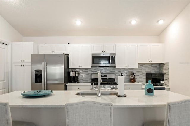 kitchen with white cabinetry, decorative backsplash, a sink, and stainless steel appliances