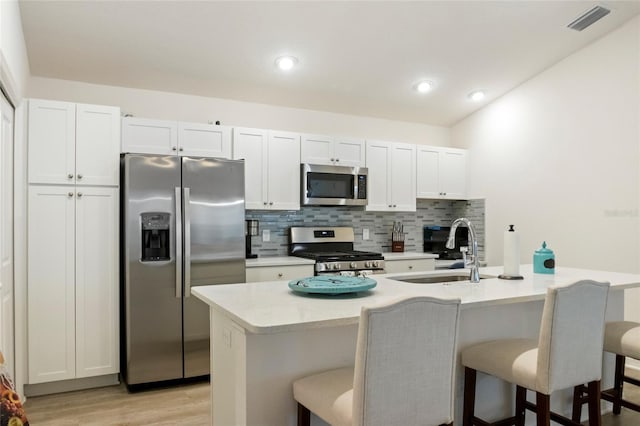 kitchen featuring a sink, backsplash, appliances with stainless steel finishes, and a breakfast bar area