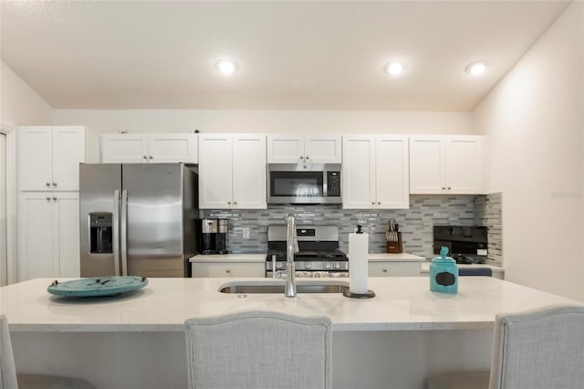 kitchen with white cabinets, backsplash, appliances with stainless steel finishes, and a sink