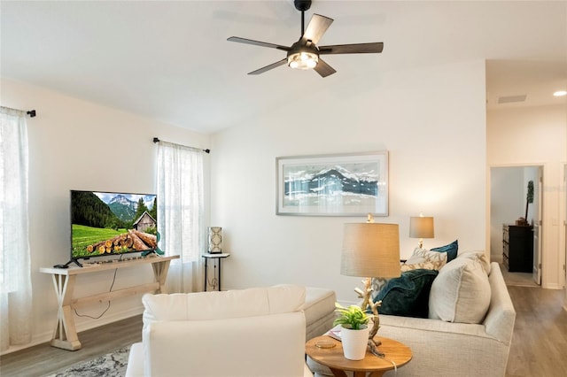 living room featuring wood finished floors, a ceiling fan, visible vents, and lofted ceiling