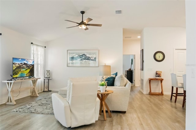 living area with light wood-style flooring, visible vents, ceiling fan, and vaulted ceiling