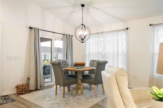 dining space featuring a notable chandelier, plenty of natural light, lofted ceiling, and wood finished floors