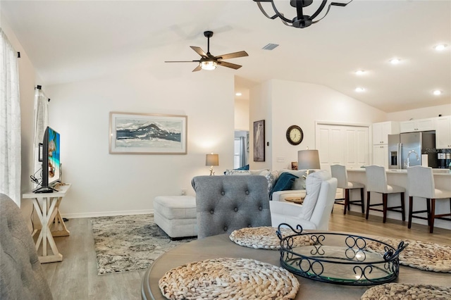 living area with visible vents, lofted ceiling, light wood-style flooring, and a ceiling fan