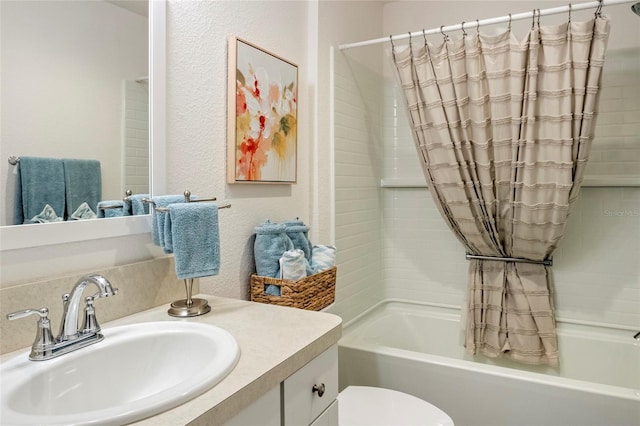 bathroom featuring toilet, shower / bath combo, vanity, and a textured wall