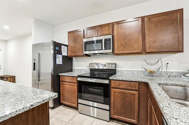 255 Blueberry Ln, Davenport, FL 33837 - kitchen with light tile patterned floors, light stone counters, a sink, and appliances with stainless steel finishes